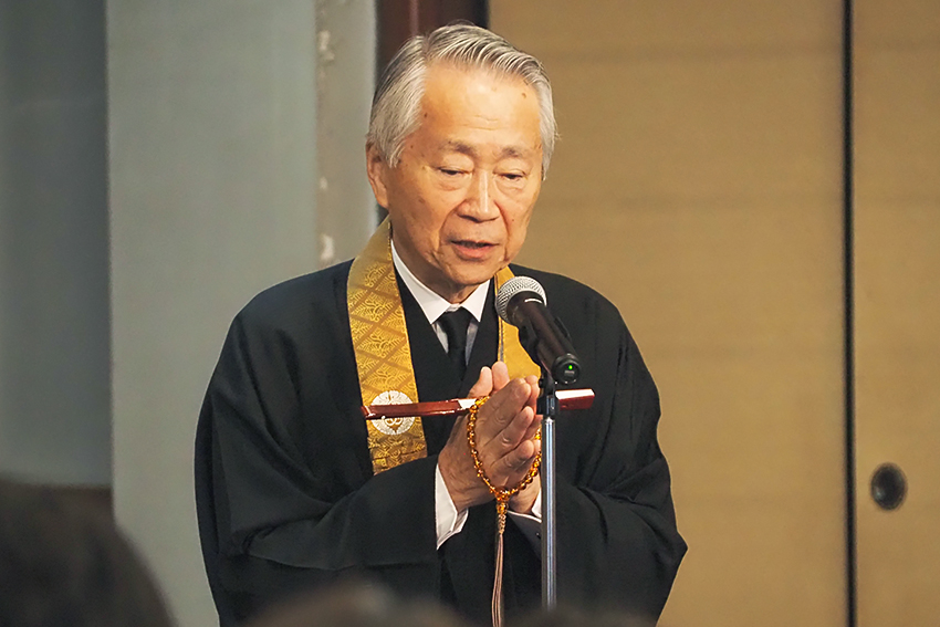 念珠を両手に掛け、中啓(朱塗りの扇)を親指に挟んで合掌される中尾史峰理事長